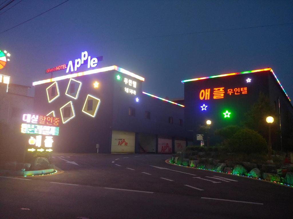 un edificio con letreros de neón por la noche en Apple Drive-in Hotel en Yeoju