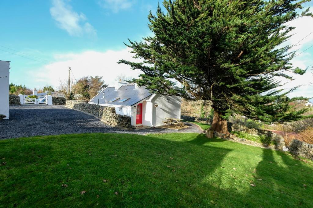 a house with a tree in front of a yard at The Cottage Hillside in Westport