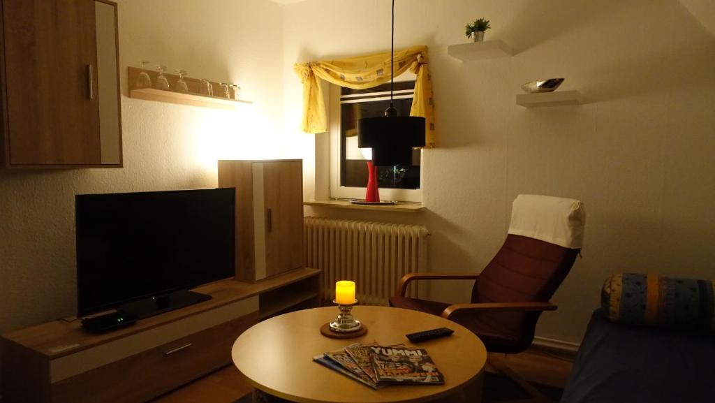 un petit salon avec une table et une télévision dans l'établissement Gemütliche 3-Zimmer - Ferienwohnung mit TV, zwischen Wilhelmshaven und Hooksiel, à Wilhelmshaven