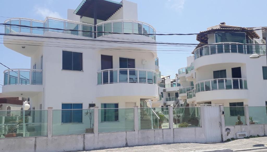 un edificio blanco con una valla delante en Apartamento na Praia dos Anjos, en Arraial do Cabo