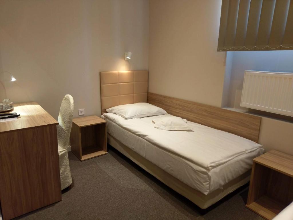 a small bedroom with a bed and a desk at Hotel Astra in Dąbrowa Górnicza