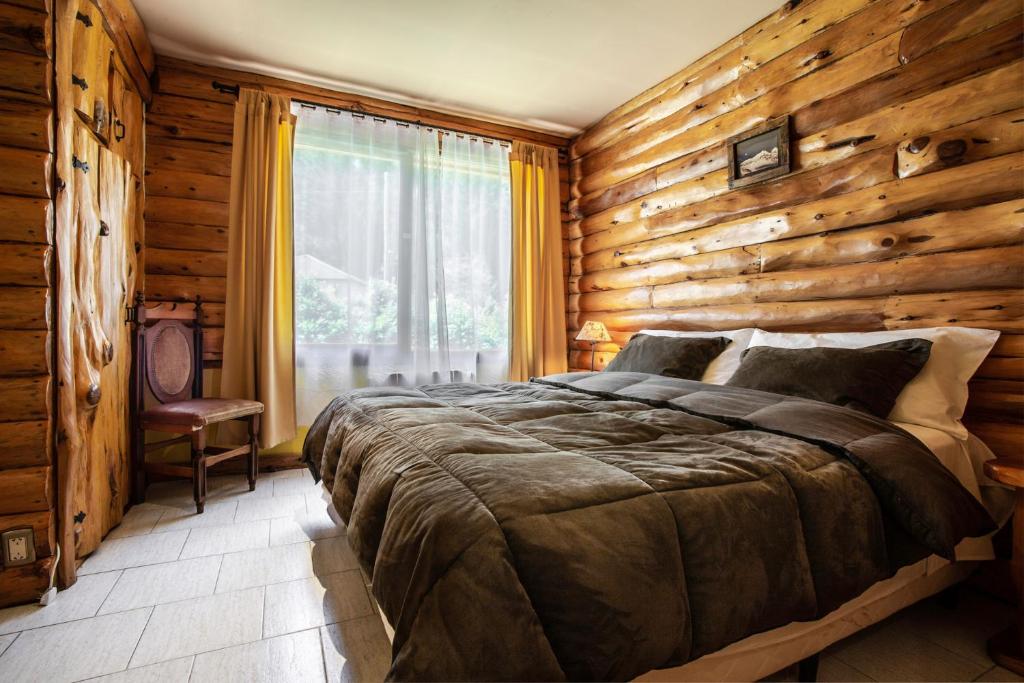 - une chambre dotée d'un mur en bois et d'un lit dans l'établissement B&B Casapuelo, à Lago Puelo