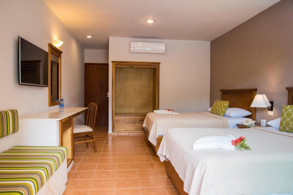 una camera d'albergo con due letti e una televisione di Tecnohotel Mérida Norte a Mérida