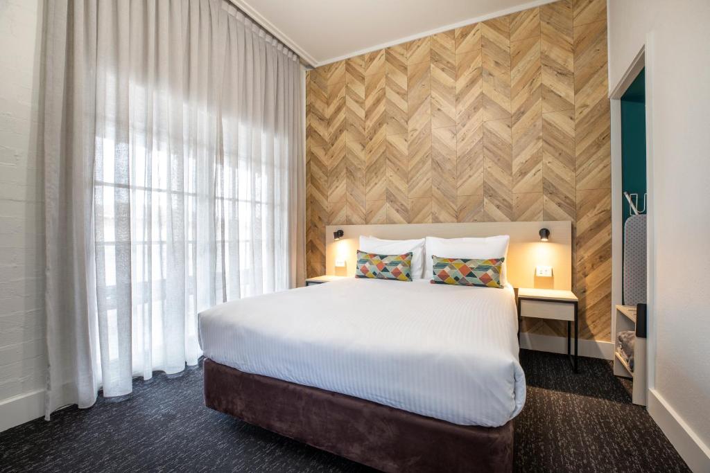 - une chambre avec un grand lit et une fenêtre dans l'établissement Nightcap at Sylvania Hotel, à Campbellfield