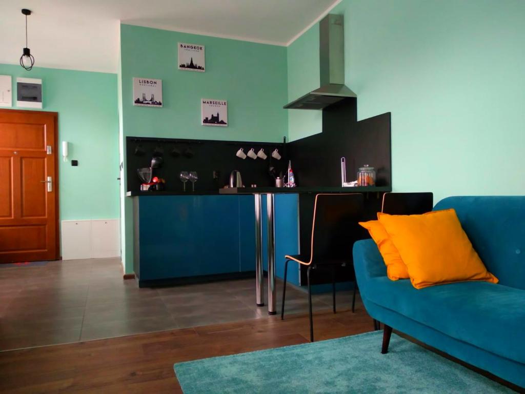 uma sala de estar com um sofá azul e uma cozinha em Apartament Santo Bartolomeo em Toruń