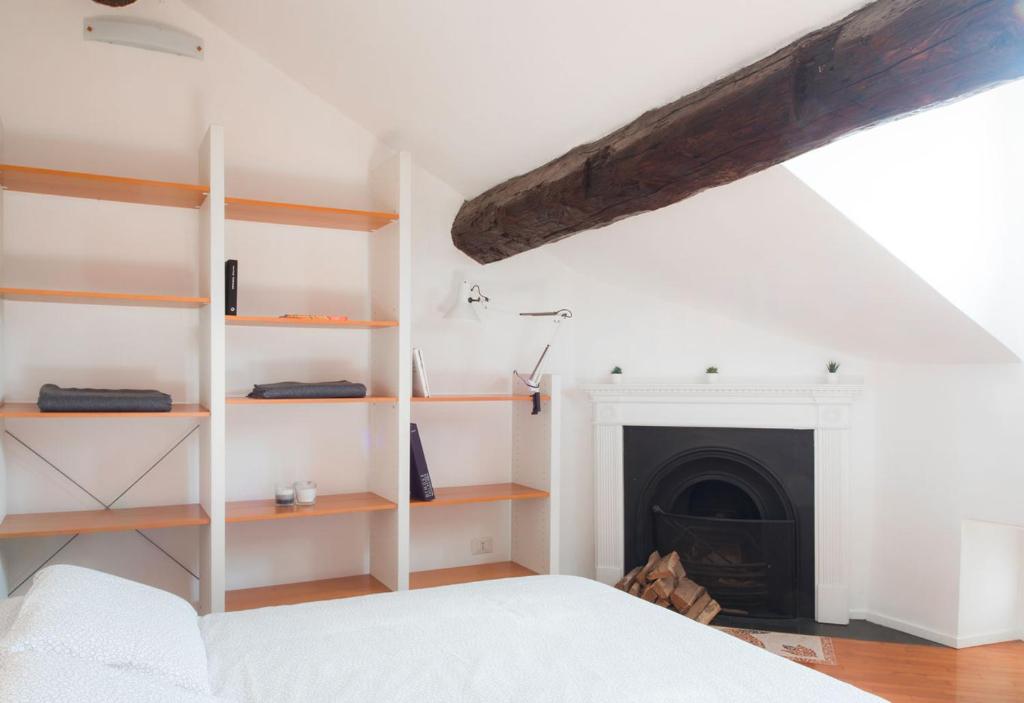 a bedroom with a white bed and a fireplace at La mansarda sui Navigli in Milan