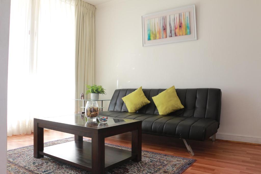 Sala de estar con sofá negro y mesa de centro en Austral Rentahome Nueva Providencia en Santiago