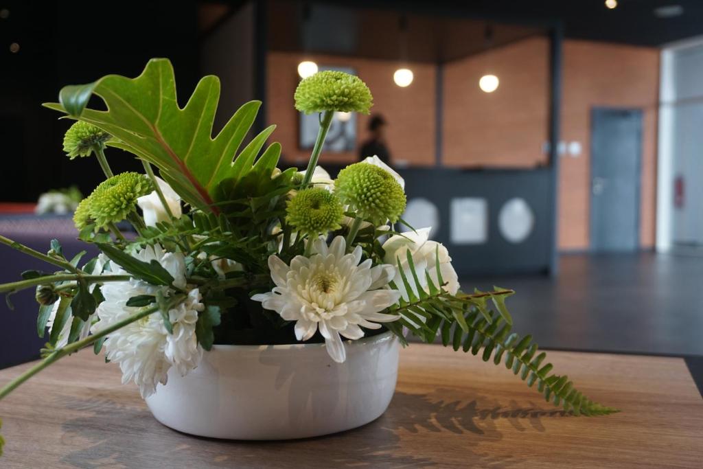 a white vase filled with white flowers on a table at ONOMO Hotel Tanger Med in Tangier