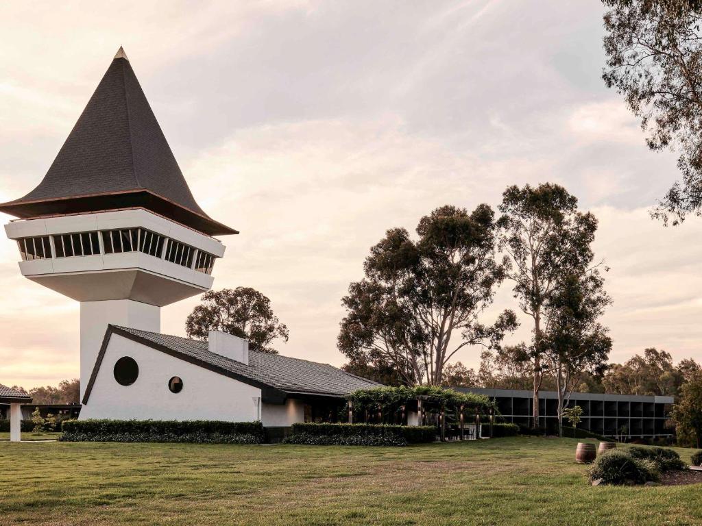 a white building with a black tower in a field at The Mitchelton Hotel Nagambie - MGallery by Sofitel in Nagambie