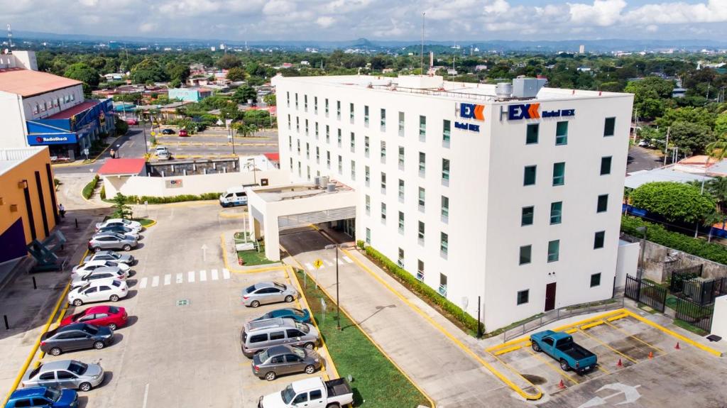 un edificio blanco con coches estacionados en un estacionamiento en Hotel Hex en Managua