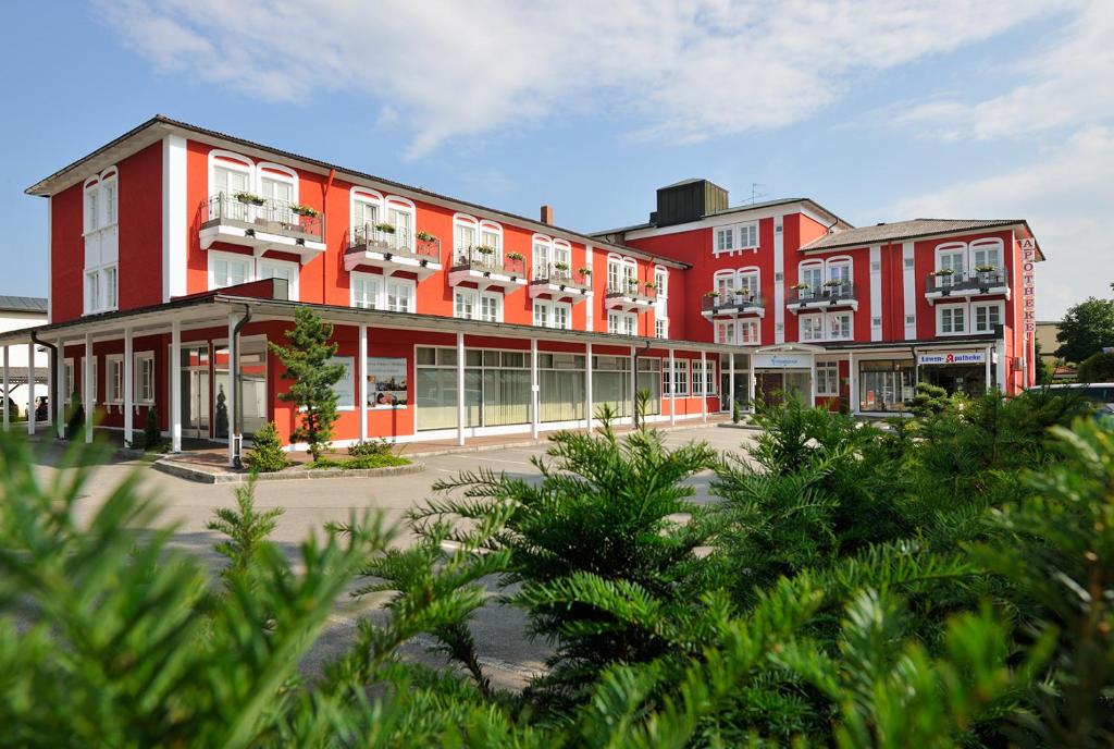 un gran edificio rojo con árboles delante de él en Johannesbad Hotel Füssinger Hof, en Bad Füssing