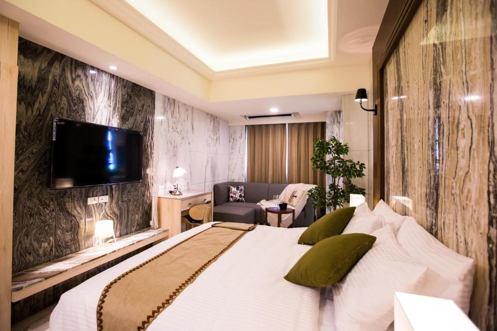 a bedroom with a bed and a tv on a wall at Hotel Maple Taiwan Boulevard in Taichung