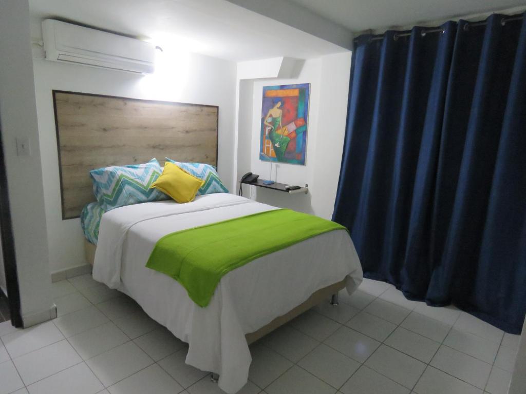 a bedroom with a large bed with a green blanket at SERENADE Lodging Rooms in Panama City