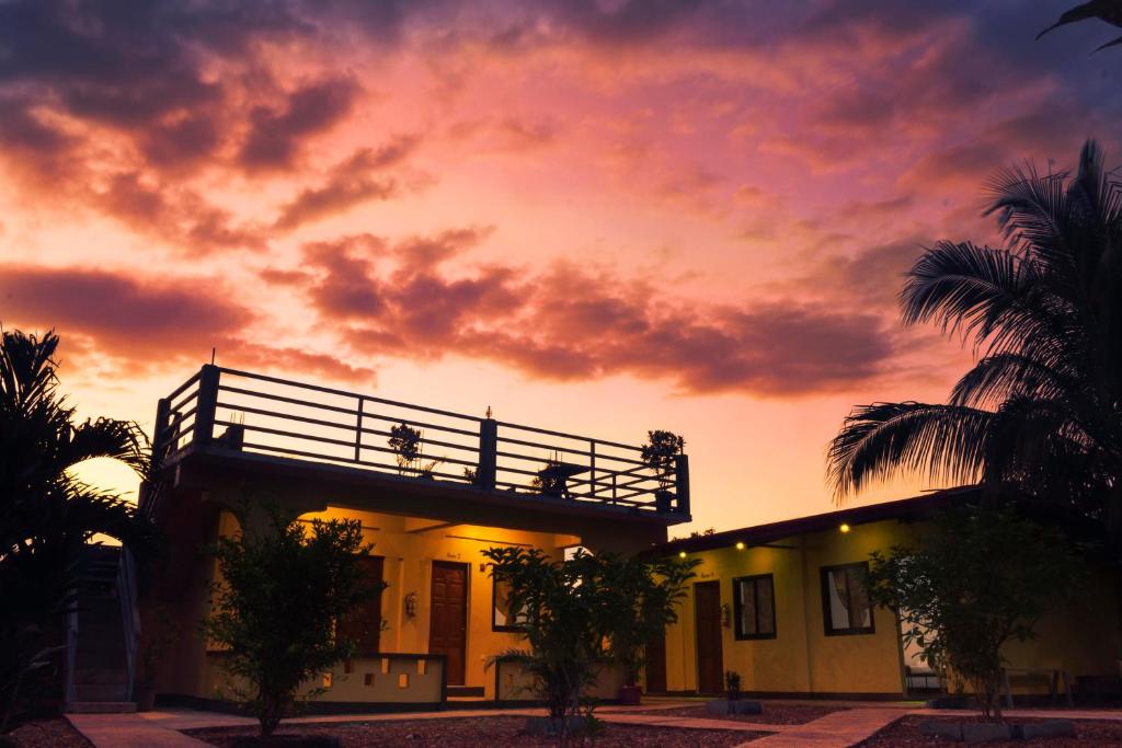 ein Gebäude mit Leuten, die bei Sonnenuntergang auf einem Balkon sitzen in der Unterkunft Angel Gabriel Homestay in Coron