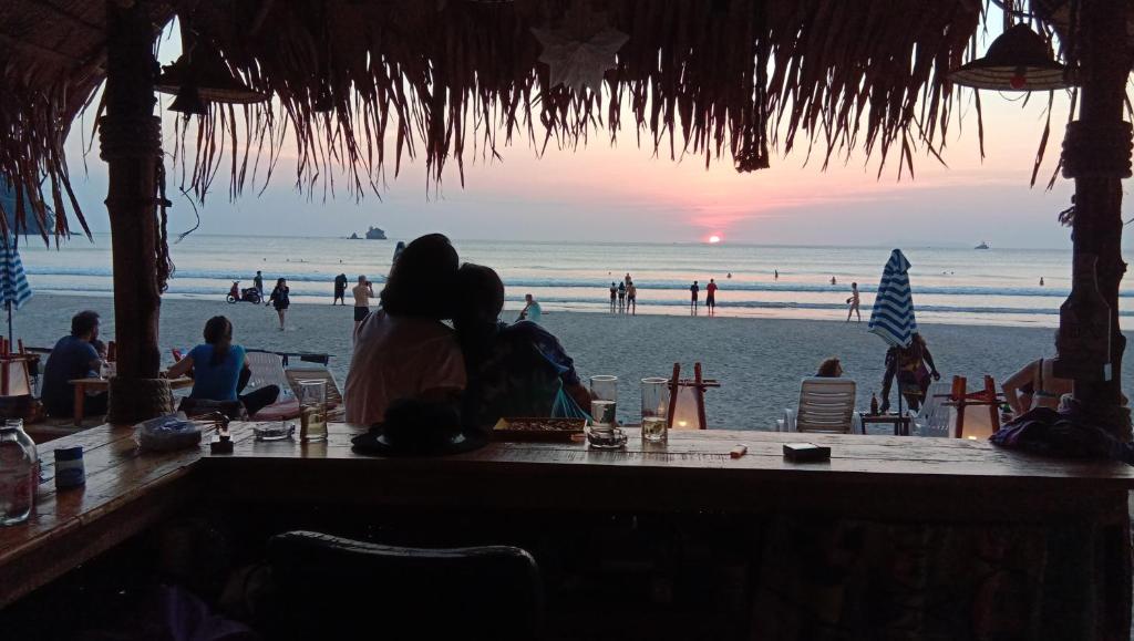a couple sitting at a table on the beach at Lazy Hut in Ko Phayam