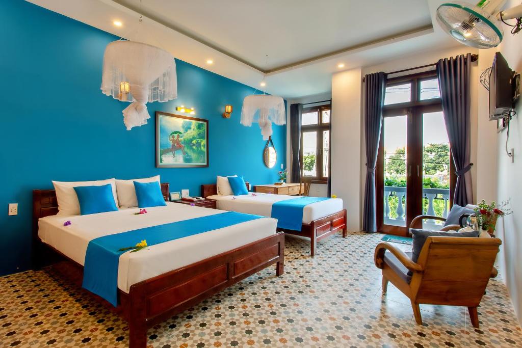 a bedroom with two beds and a blue wall at Lang Dong An Bang in Hoi An