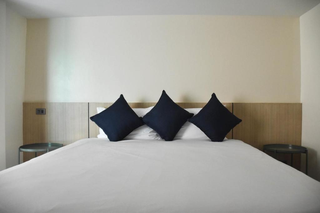 - un lit blanc avec des oreillers bleus dans l'établissement Stay Inn Nathon Samui, à Nathon