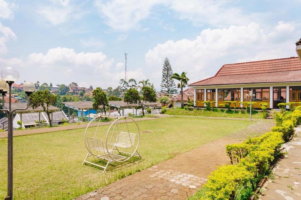 a white chair sitting in the grass in front of a house at RedDoorz @ Hotel Damanaka Pangalengan in Pengalongan