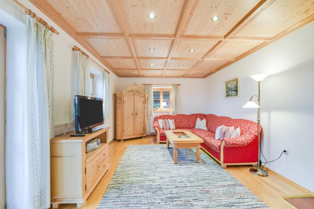 a living room with a red couch and a tv at Ferienwohnung Morgenrot in Wackersberg
