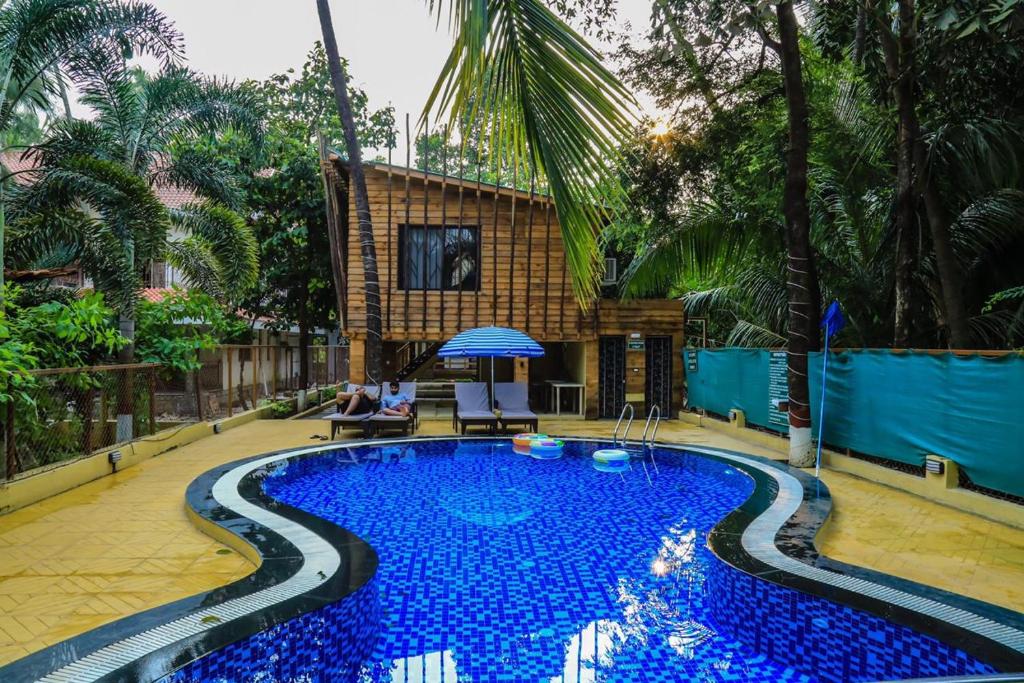 a swimming pool with blue water in front of a house at Coconut Beach Farm in Alibaug