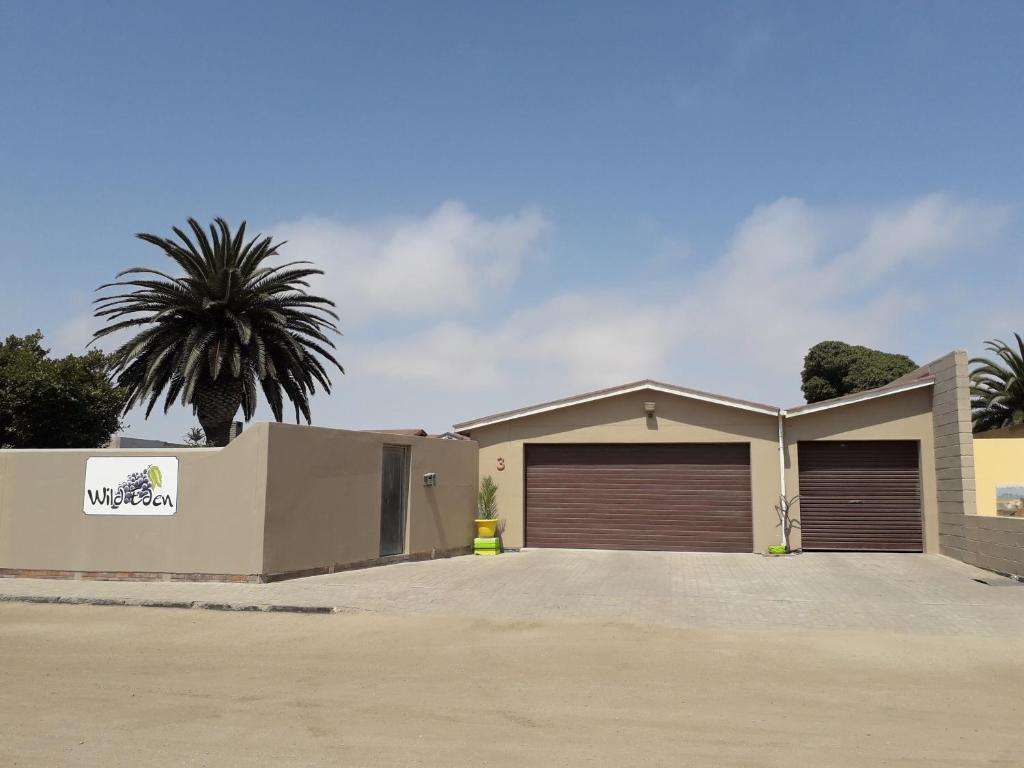 a house with two garage doors and a palm tree at Wild Eden Self-Catering Accommodation in Swakopmund