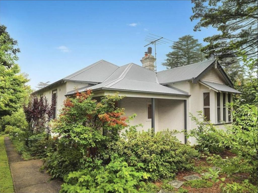 una casa blanca con techo y algunos arbustos en Mintie Cottage on Leura Mall, en Leura