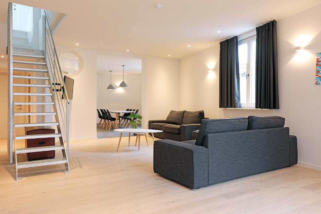 een woonkamer met een zwarte bank en een trap bij Loft vakantiehuis in Veurne