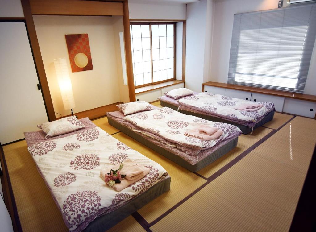 3 Betten in einem Zimmer mit 3 Fenstern in der Unterkunft Guest room Kamakura Nagomi -Hydrangea- in Kamakura