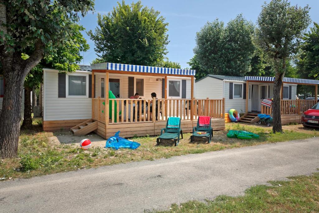 una casa con un porche con dos sillas y gente en ella en Albatross Mobile Homes on Camping San Francesco, en Duna Verde