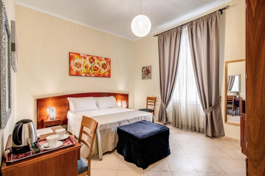 a hotel room with a bed and a desk and window at Residenza Praetoria in Rome