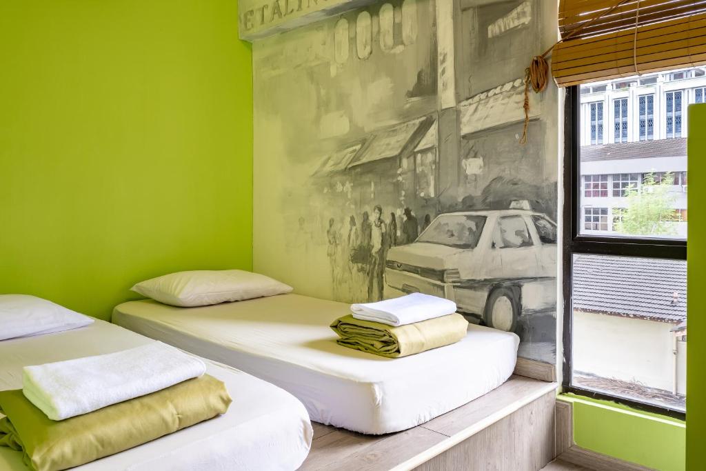 two beds in a green room with a picture on the wall at PODs The Backpackers Home & Cafe, Kuala Lumpur in Kuala Lumpur