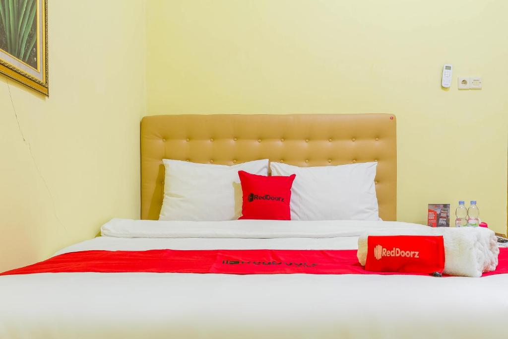 uma cama com almofadas vermelhas e brancas em RedDoorz Syariah @ Puri Kalijaga Street em Cirebon