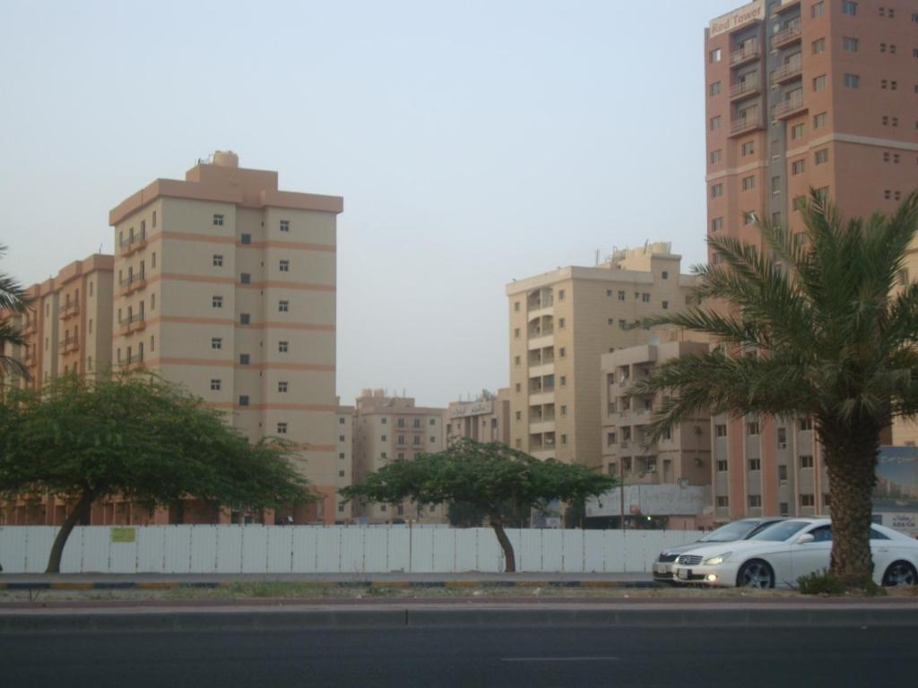 um carro estacionado em frente a alguns edifícios altos em Red Tower Furnished Apartments em Kuwait