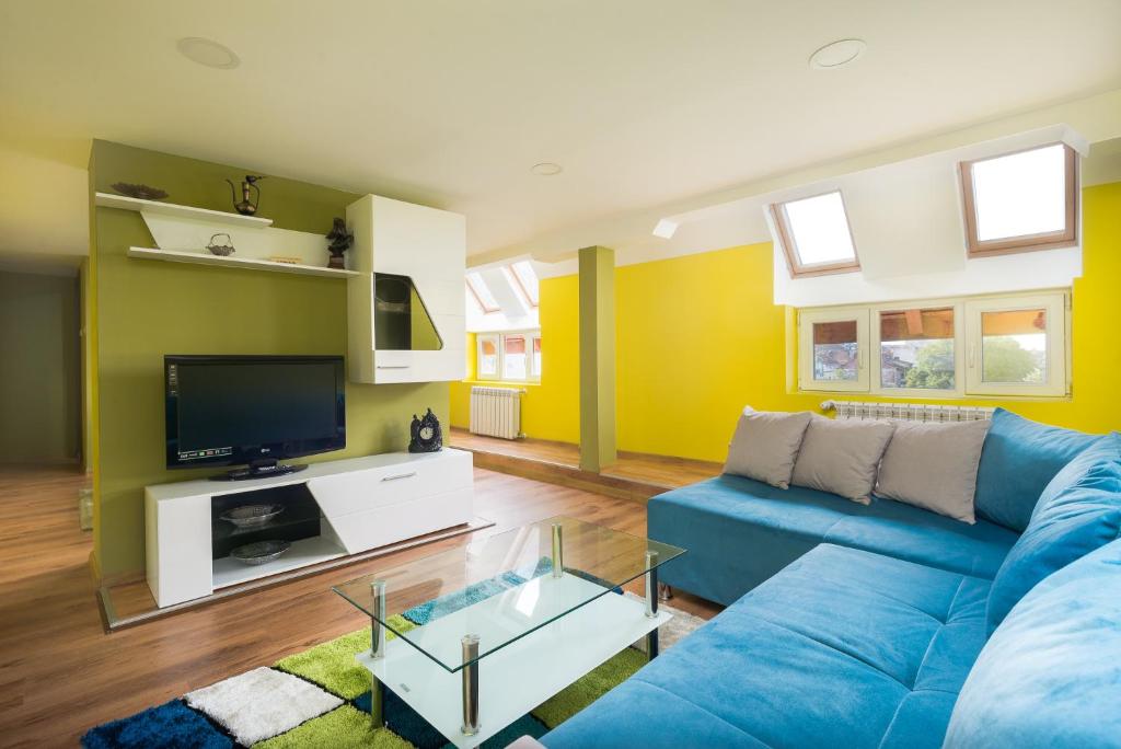 Serdika Round Tower Apartments في صوفيا: غرفة معيشة مع أريكة زرقاء وتلفزيون