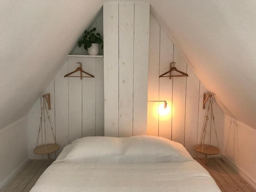 a bedroom with a white bed and a light at Zoute Zeelucht in Katwijk aan Zee