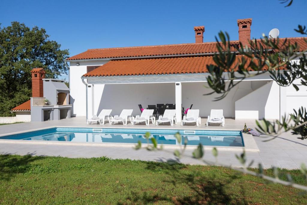 een huis met een zwembad met stoelen en een tafel bij Villa Piljan in Bokordići