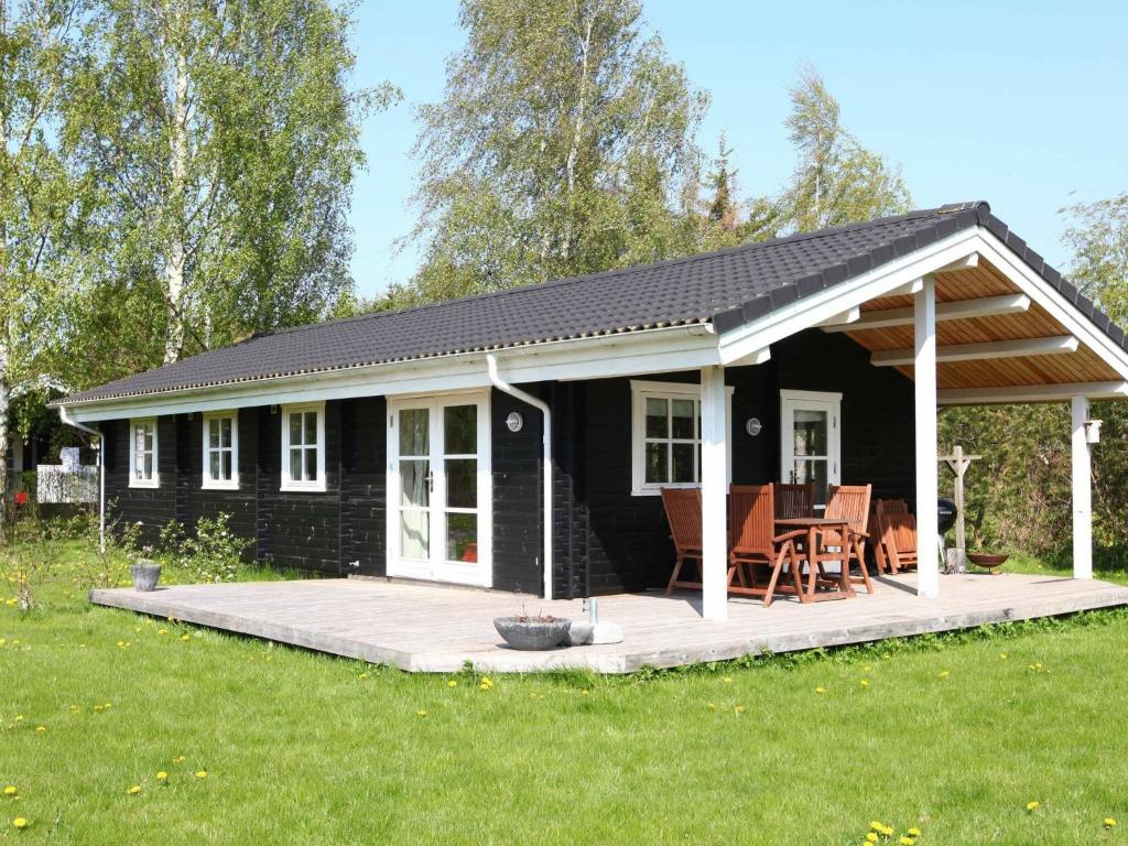 a black cottage with a porch and a deck at 6 person holiday home in Skibby in Skibby