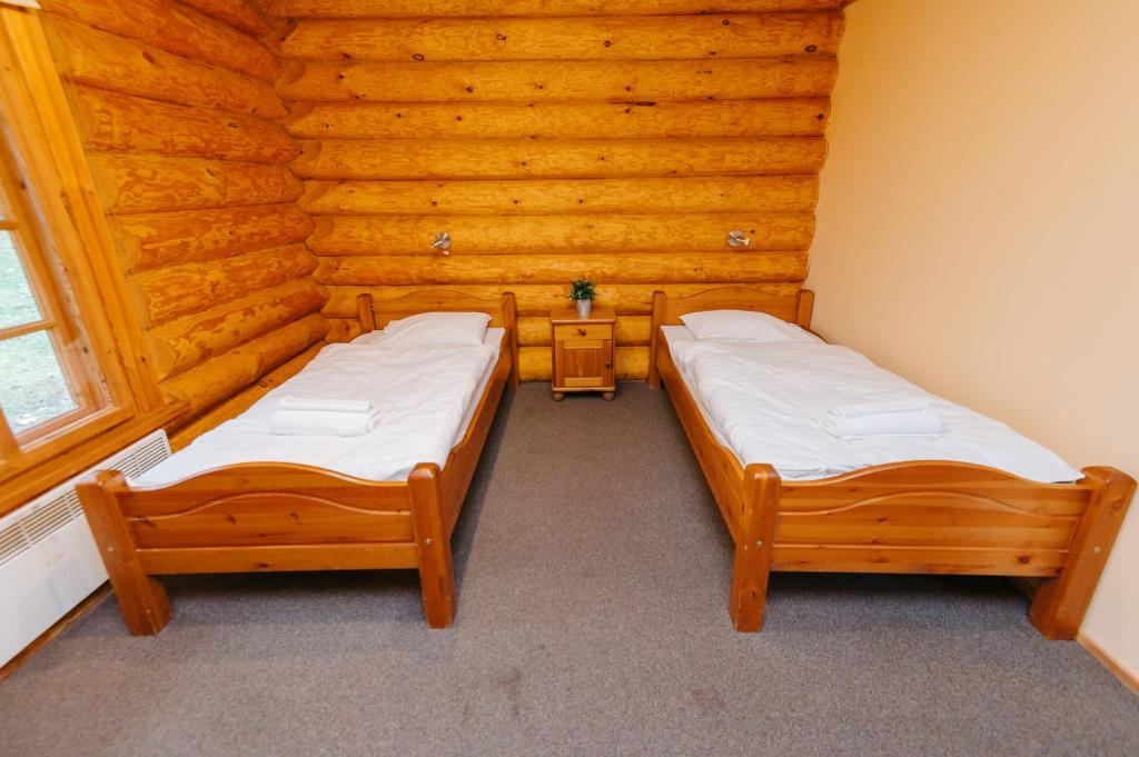 - 2 lits dans une chambre dotée de murs en bois dans l'établissement Atpūtas parks Lācītes, à Gulbene