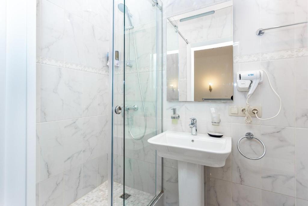 a white bathroom with a sink and a shower at Casa Leto in Saint Petersburg