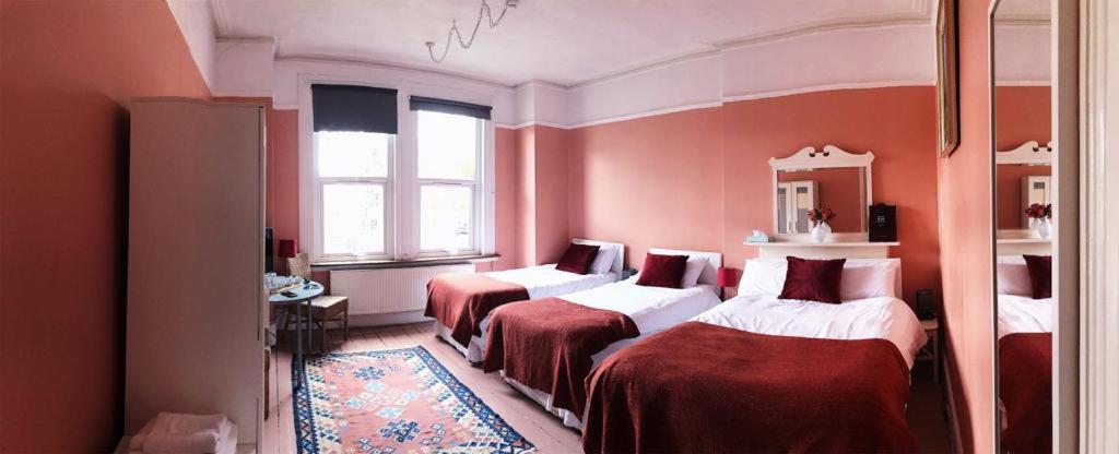 2 camas en una habitación con paredes rojas en Caspian Hotel en Londres
