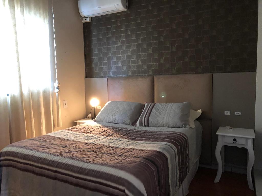 a bedroom with a large bed with a brick wall at Mini Casa na praia! in Bombinhas