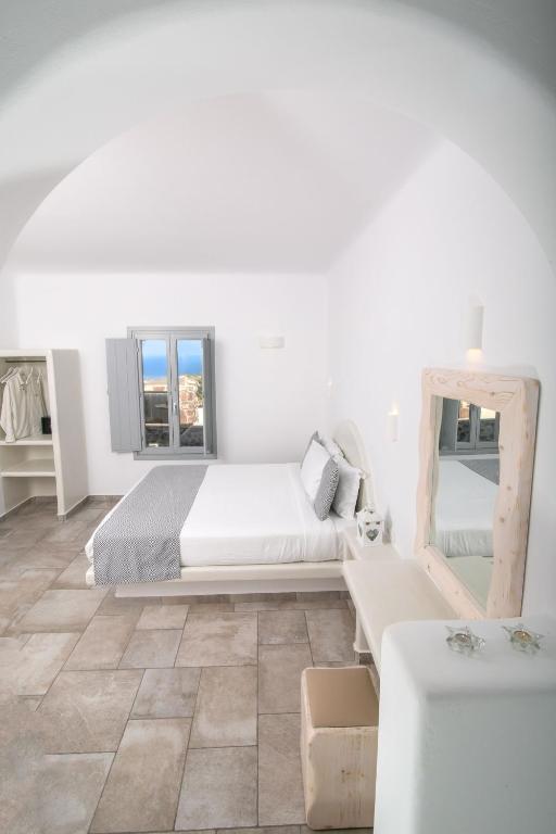 a white bedroom with a bed and a living room at Anemoessa Villa in Oia