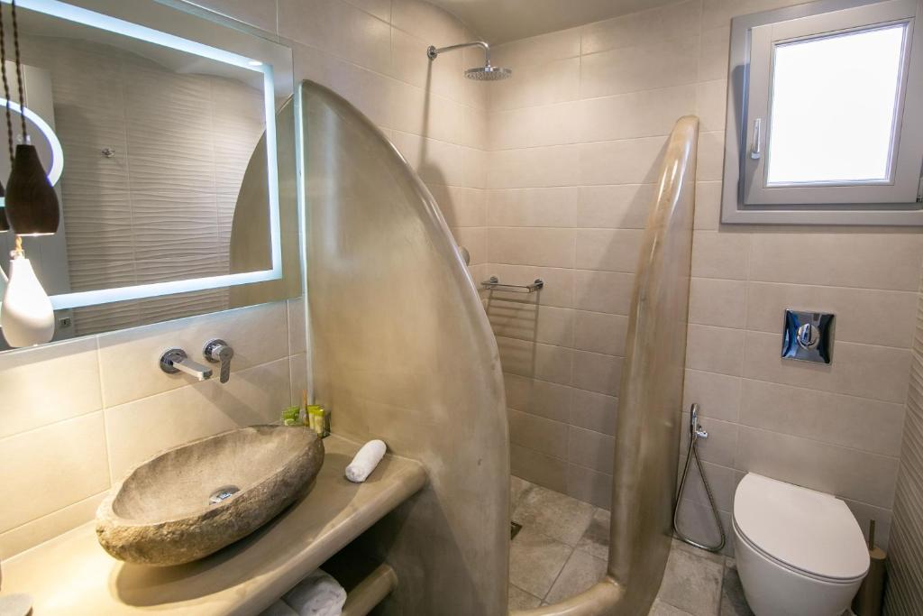 a bathroom with a sink and a shower and a toilet at Anemoessa Villa in Oia