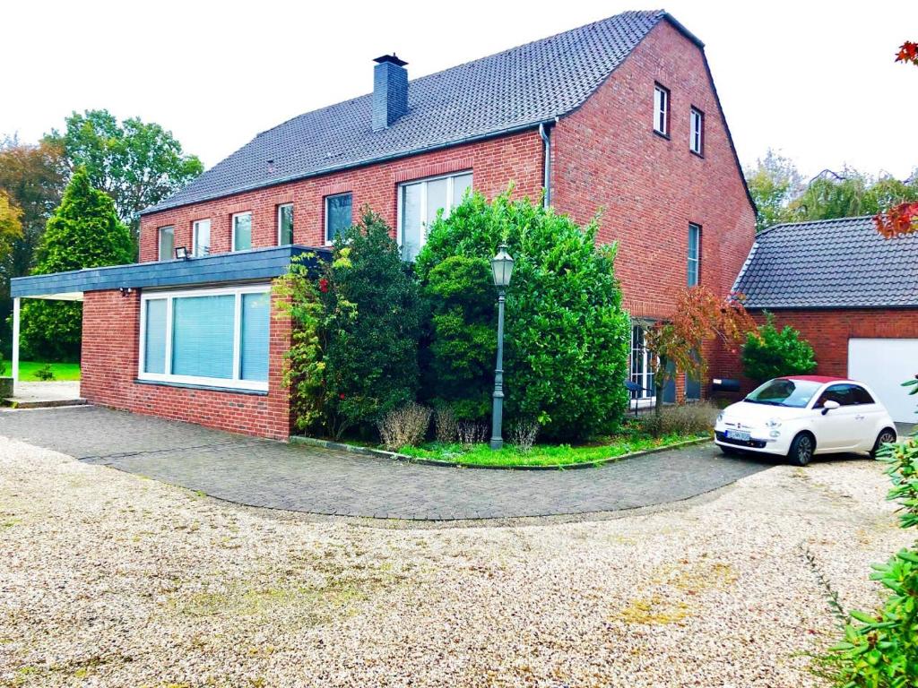 una casa de ladrillo rojo con un coche blanco aparcado delante en Ferienhaus Landhaus EMG Kempen, in Alleinlage nahe Düsseldorf und Venlo, en Tönisvorst