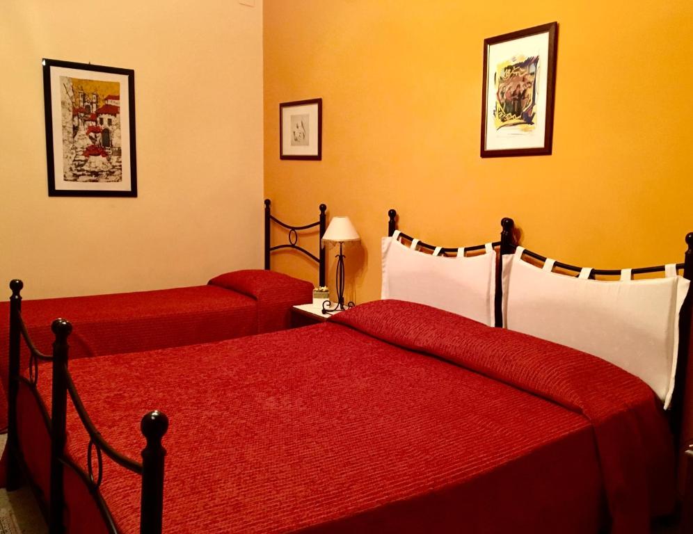 a bedroom with two beds with red sheets at A Casa Di Mamma in Milazzo