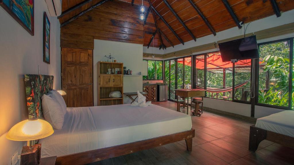 Boca Tapada Lodge في Boca Tapada: غرفة نوم بسرير كبير في غرفة بها نوافذ