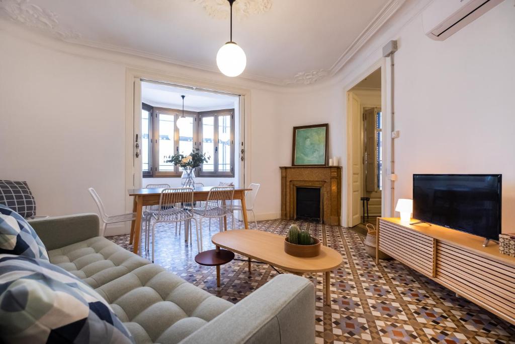 ein Wohnzimmer mit einem Sofa und einem TV in der Unterkunft b42 - MODERNIST APARTMENT FOR LARGE GROUPS IN EIXAMPLE in Barcelona