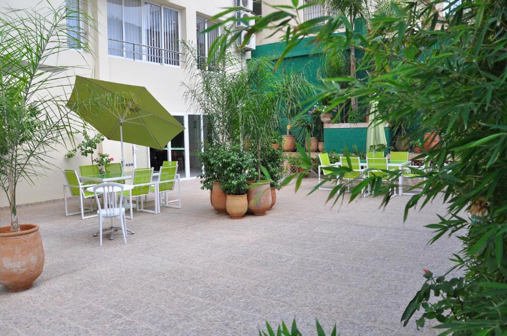 een patio met stoelen en een tafel met een parasol bij Across Hotels & Spa in Fès