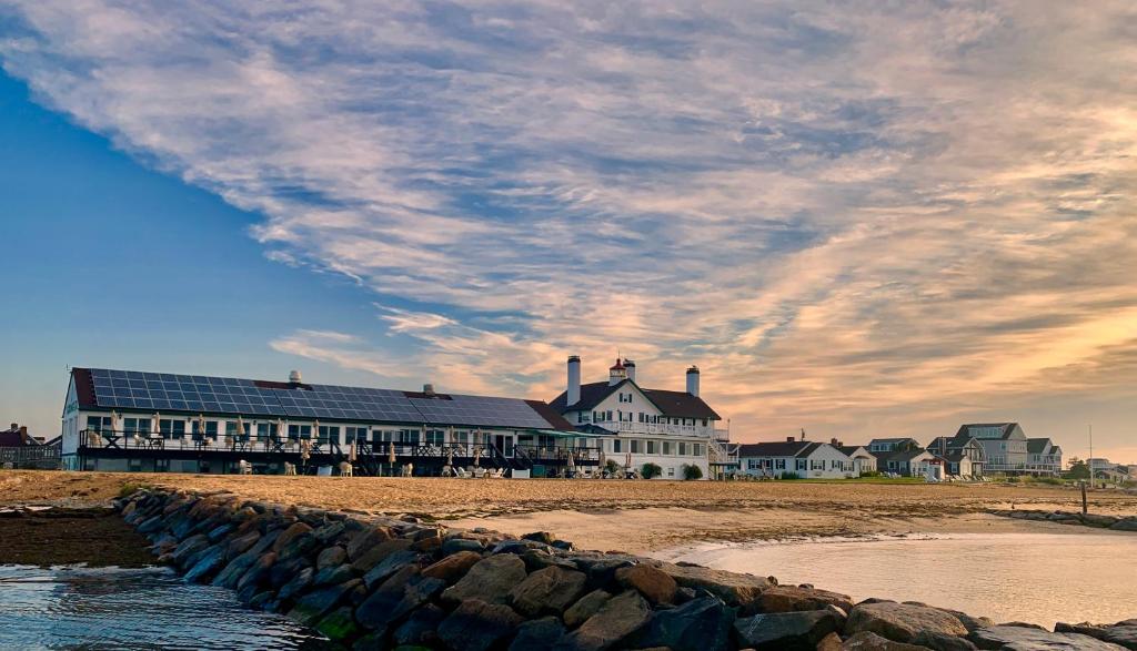 a large building on the beach with a cloudy sky at Lighthouse Inn Cape Cod in West Dennis