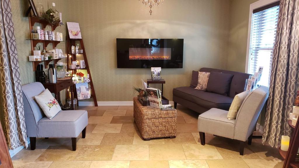 a living room with a couch and chairs and a tv at The Lakehouse Inn Geneva in Geneva-on-the-Lake